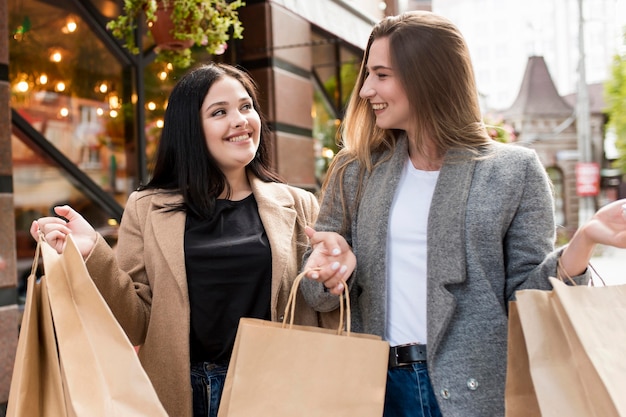 Best friends holding shopping bags outdoors