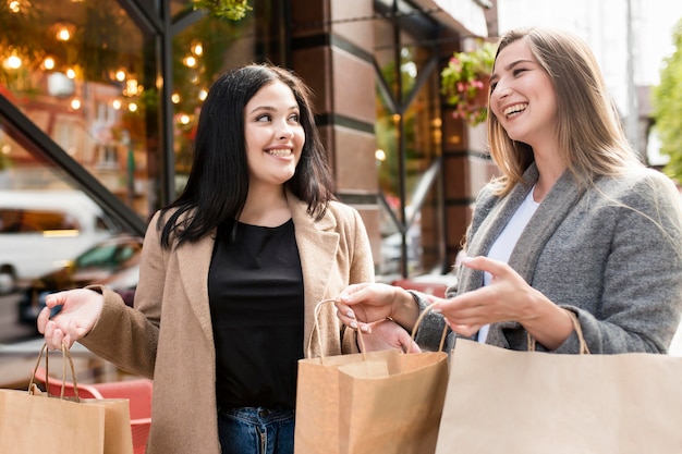 Free photo best friends holding shopping bags