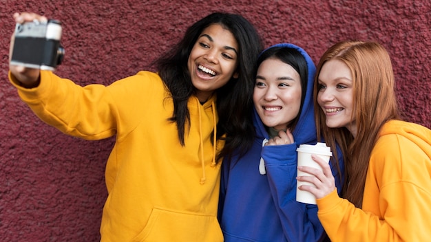 Free photo best friends in hoodies taking a selfie with a camera