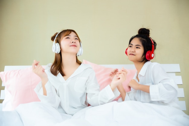 Best friends joyful with listening song in bedroom