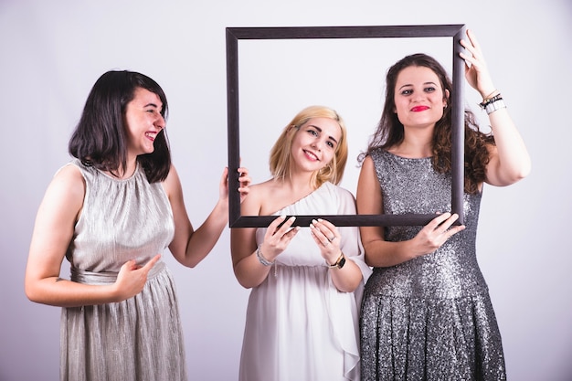 Free photo best friends laughing and holding a frame