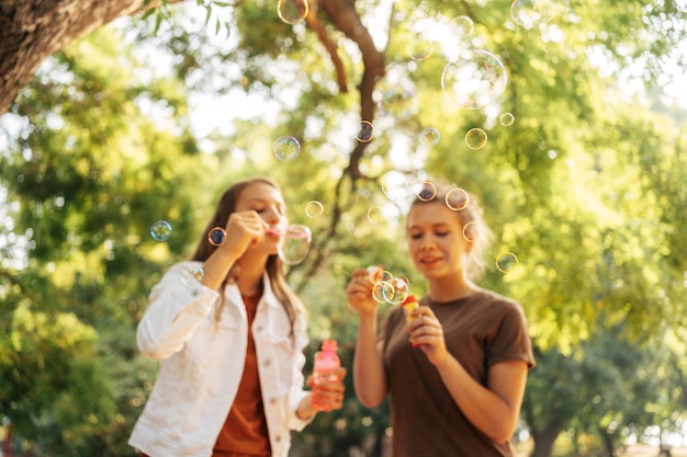 Best friends making soap bubbles outside