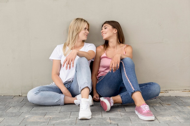 Free photo best friends posing on a gray wall