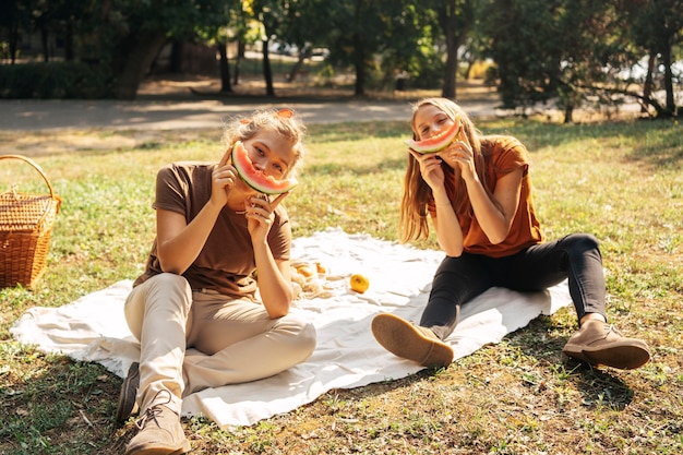 Free photo best friends posing while eating watermelon