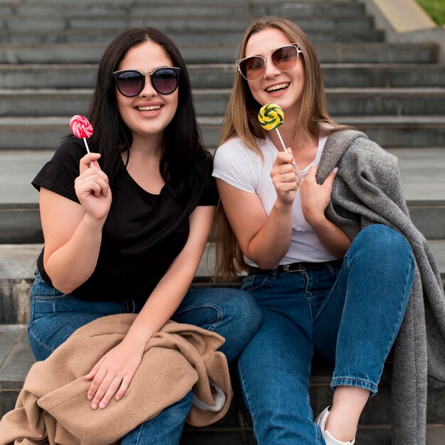 Best friends posing with lollipops outside