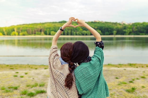 Best friends showing heart sign over beautiful landscape on the