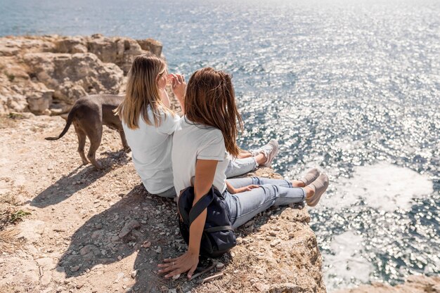 Best friends sitting on rocks next to the ocean
