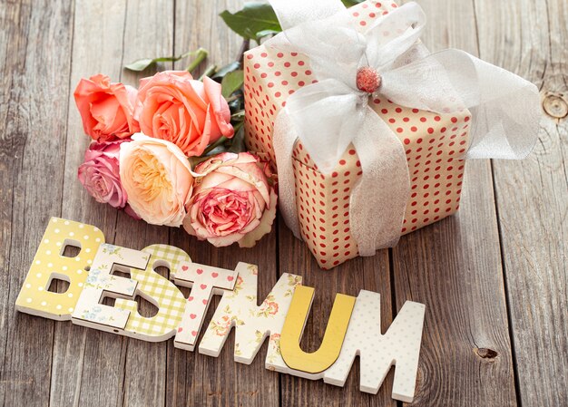 Best Mum written in multicolored wooden letters, present and fresh rose. Holiday concept.