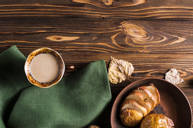 Beverage and baked apples near napkin and leaves