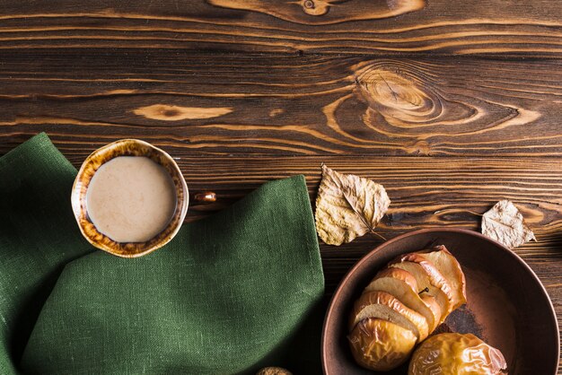 Beverage and baked apples near napkin and leaves