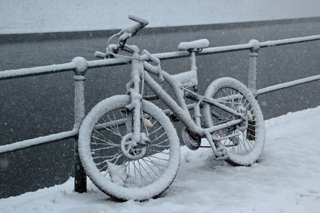 Bicycle leaned against a fence covered in snow