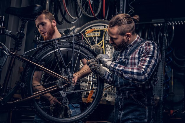 自転車の部品とホイールを背景にしたワークショップの自転車整備士。