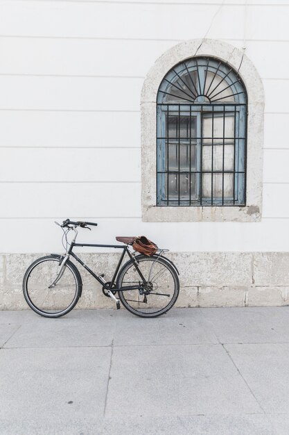 Bicycle parked on white wall with window