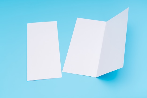 Бифолд белый шаблон бумаги на синем фоне.