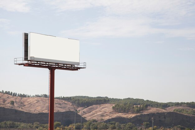 Big billboard advertising sign with mountains and sky in the background