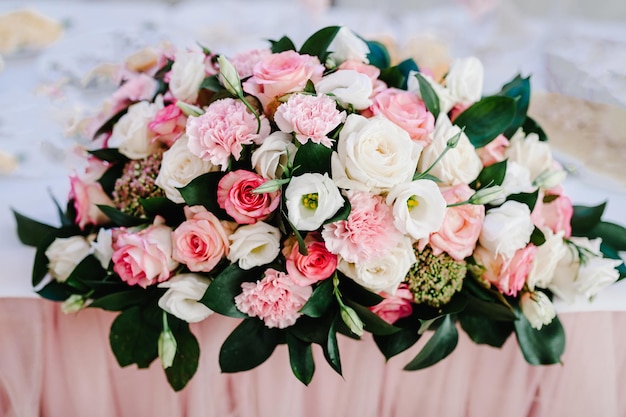 Большой букет из живых цветов, розовых, белых роз и зелени в вазе. свадебные цветы, букет невесты крупным планом. домашний декор на столе, винтажном стиле. предметы украшения.