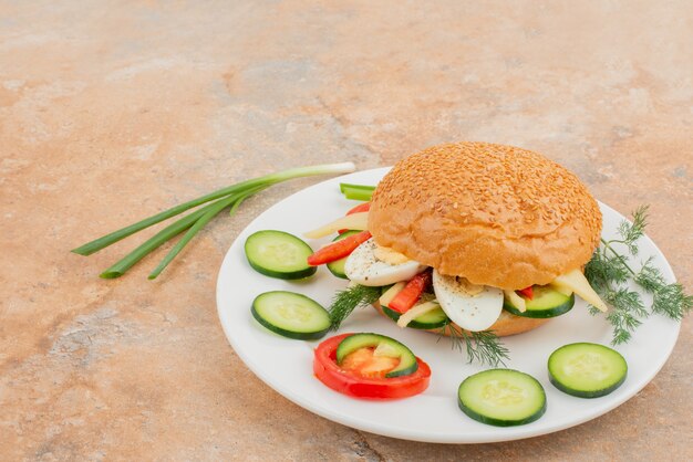 Big burger with cucumber and egg .