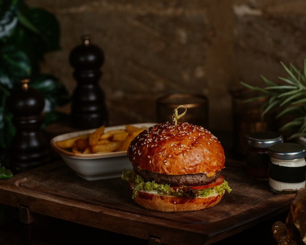 Foto gratuita grande hamburger con bistecca e patatine fritte alle erbe