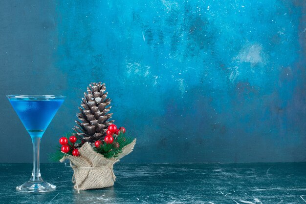 青い飲み物のガラスのカップと大きなクリスマスの松ぼっくり。