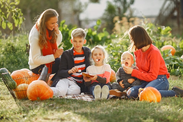 Big family sitting on a garden near many pumpkins