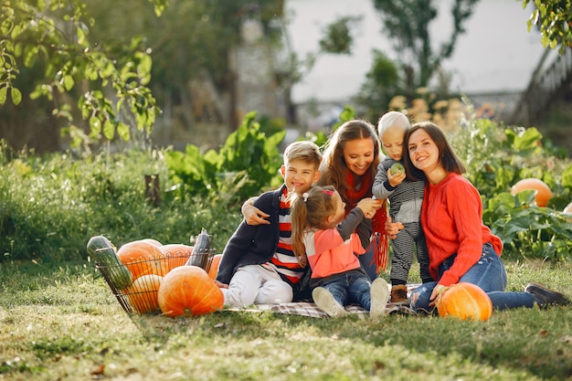 Big family sitting on a garden near many pumpkins