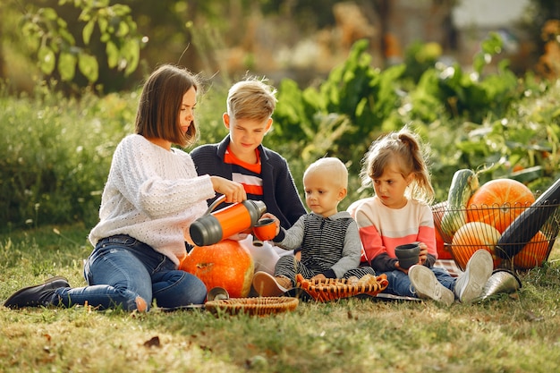 Big family sitting on a garden near many pumpkins