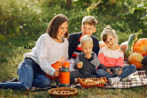 Big family sitting on a garden near many pumpkins