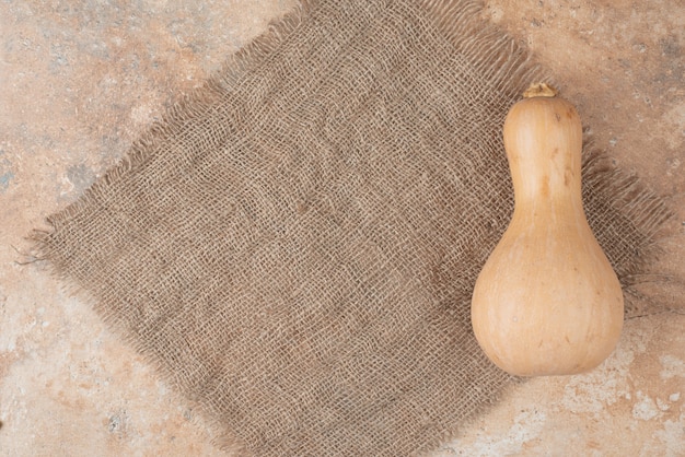 Free photo big fresh pumpkin on burlap on marble.