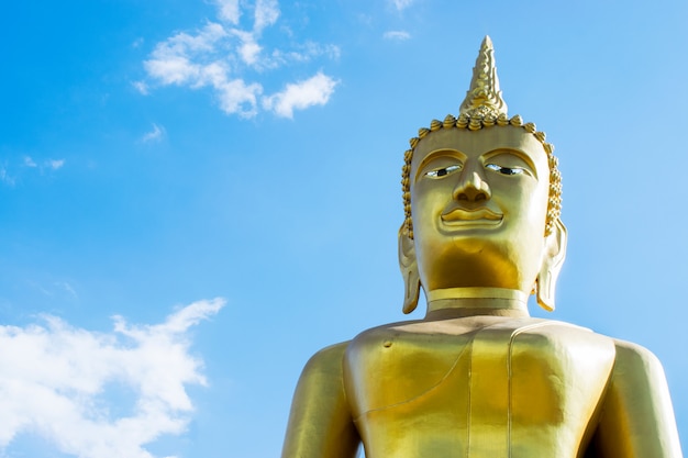 青い​空​を​背景​に​大きな​黄金​の​仏像
