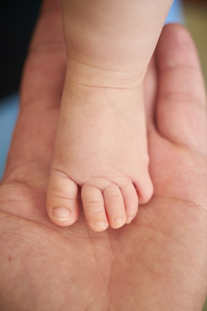 Big hand holding a baby foot