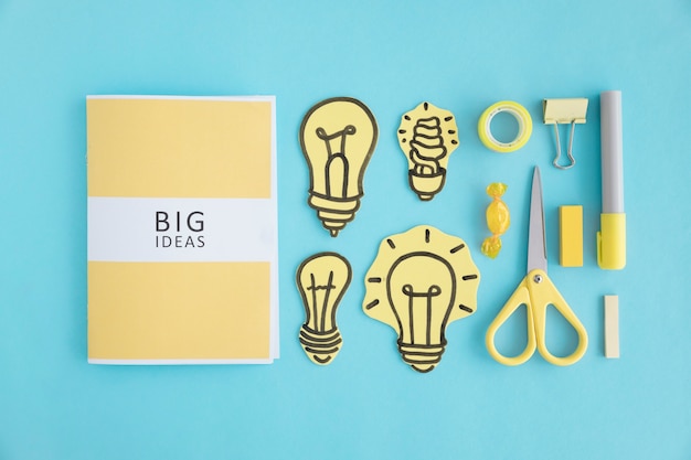 Big ideas book with different light bulb and stationery on blue backdrop