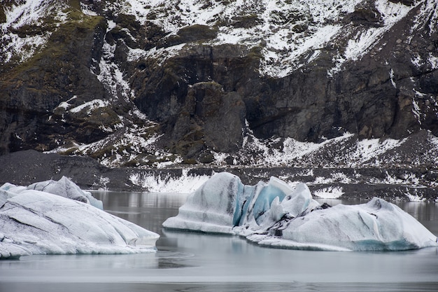 Большие куски пресного льда в замерзшем озере в окружении скалистых гор