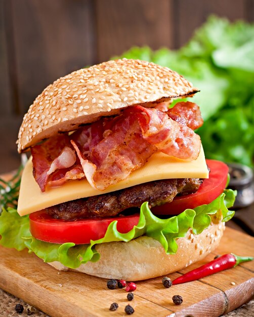Foto gratuita big sandwich - hamburger con manzo, formaggio, pomodoro e pancetta fritta