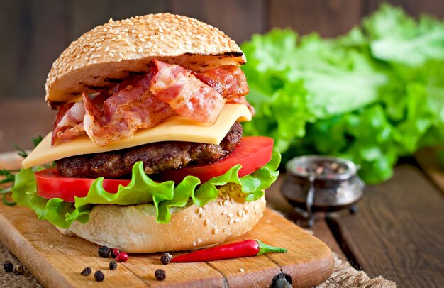 Большой бутерброд - гамбургер с говядиной, сыром, помидорами и жареным беконом