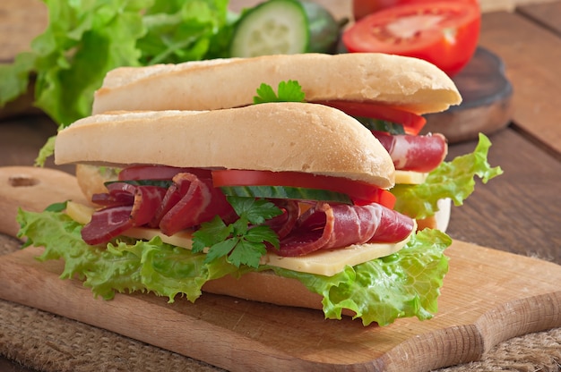 Big sandwich with raw smoked meat on a wooden surface