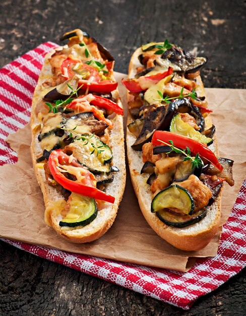 Big sandwich with roasted vegetables (zucchini, eggplant, tomatoes) with cheese and thyme on old wooden background