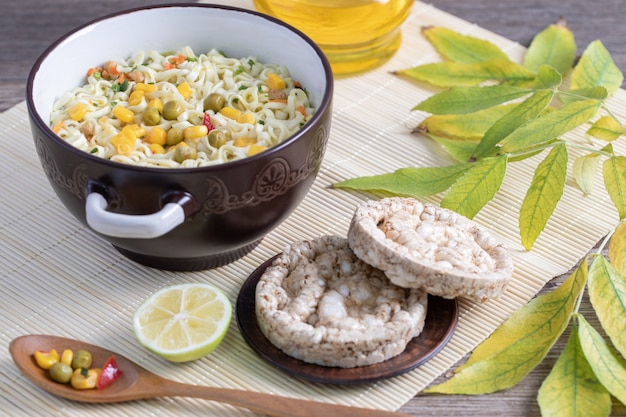A big saucepan of delicious noodles with corns, peas and round bread crusts 