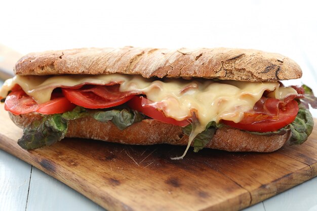 Big vegan sandwich with vegetables and cheese on wooden board table