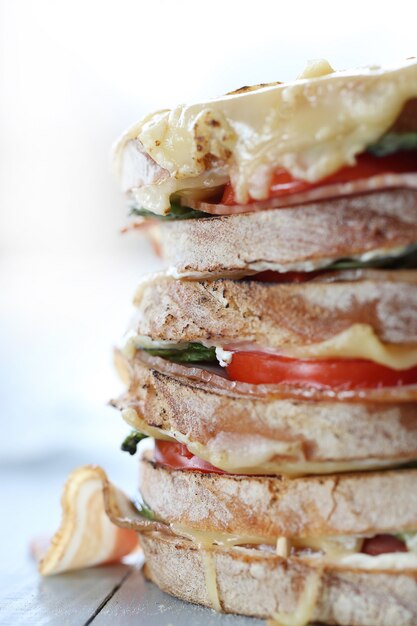 Big vegan sandwich with vegetables and cheese on wooden board table