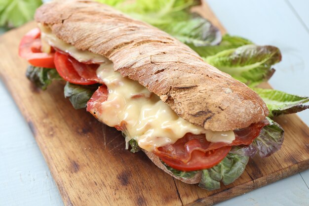 Big vegan sandwich with vegetables on wooden board table