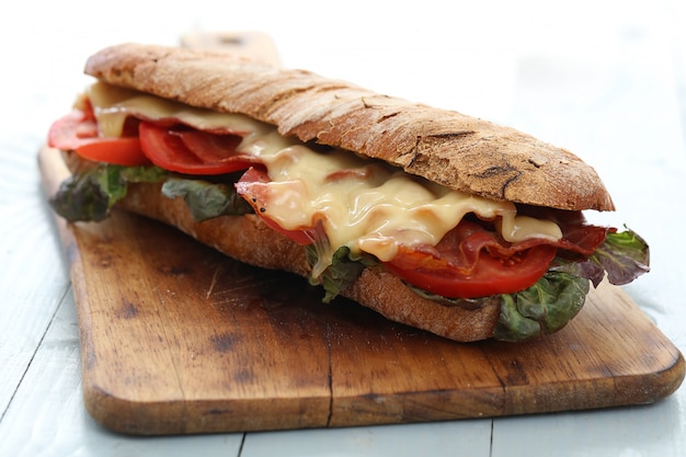 Big vegan sandwich with vegetables on wooden board table