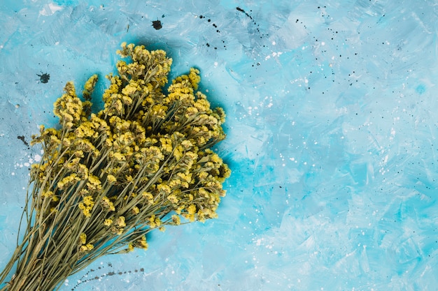 Foto gratuita grande mazzo di fiori gialli sul tavolo blu