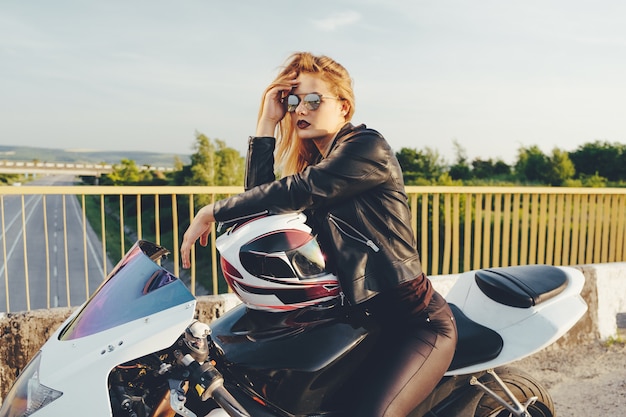 Foto gratuita ragazza del motociclista in vestiti di cuoio su una moto