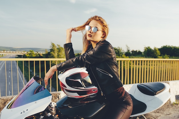 Foto gratuita ragazza del motociclista in vestiti di cuoio su una moto