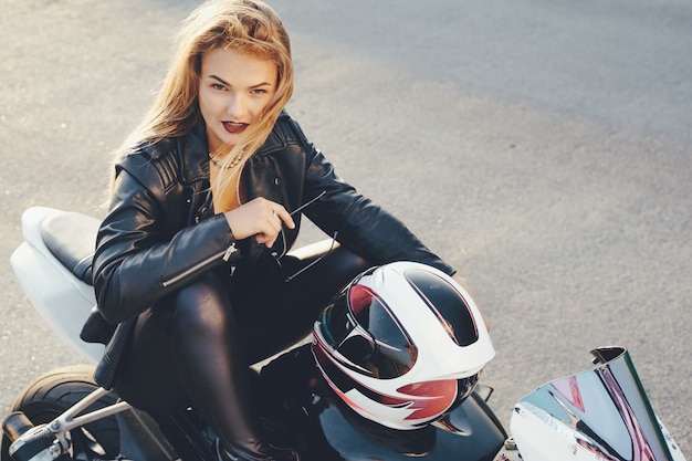 Foto gratuita ragazza del motociclista in vestiti di cuoio su una moto