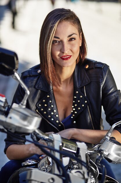 Biker girl in a leather jacket on a motorcycle