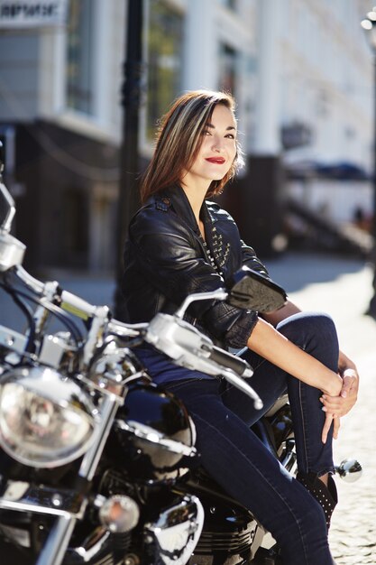 Biker girl in a leather jacket on a motorcycle