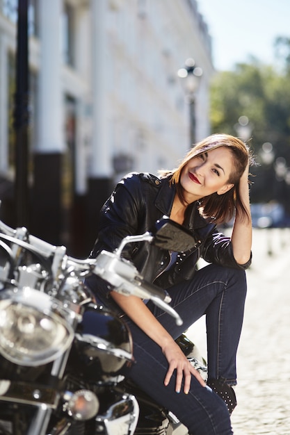 Biker girl in a leather jacket on a motorcycle