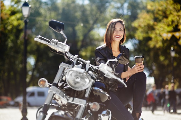 Байкер девушка в кожаной куртке на мотоцикле