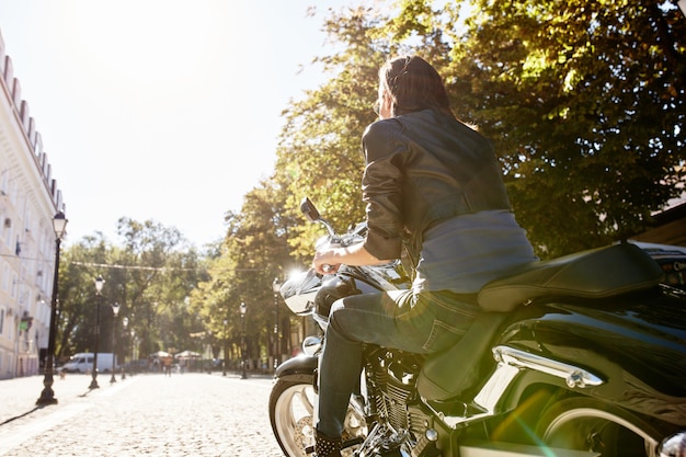 Biker girl in a leather jacket on a motorcycle